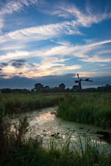 Old pumping windmill in the dutch countryside under invading clouds