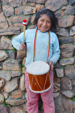Little native american girl playing traditional sikuri drum.