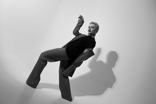 Stylish young woman in a suit in the studio on a white background. Short haircut. Black and white photo.