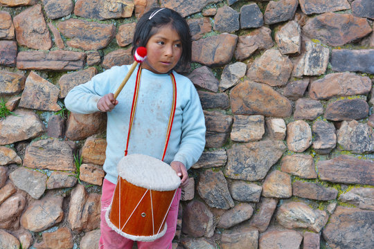 Sad little latin american girl playing typical sikuri drum.