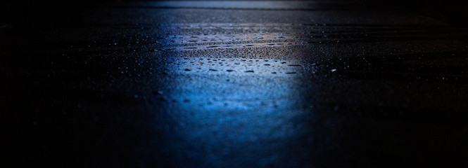 Wet asphalt, night scene of an empty street with a little reflection in the water, the night after the rain. Abstract dark neon background with a wet surface, reflection, neon, glare, blurred bokeh.