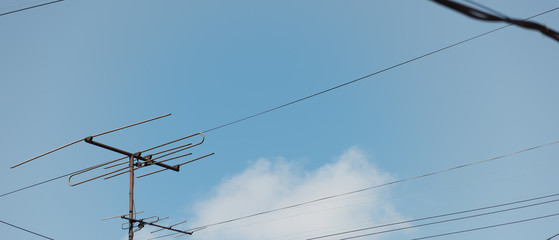 TV antenna and wires against the sky with clouds