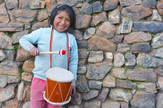 Little native american girl playing traditional sikuri drum.