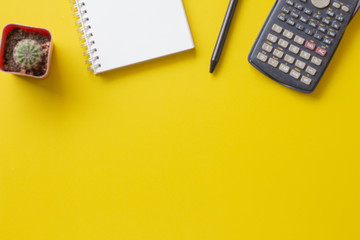 notebook with pen and calculator on yellow background