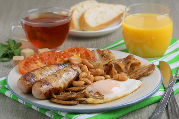 Classic English breakfast served: eggs, bacon, beans, juice and tea