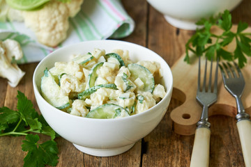 Cauliflower salad with cucumbers and eggs on a wooden background