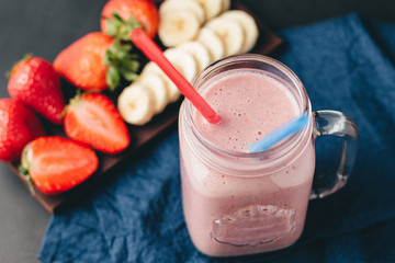 Smoothie with strawberry and banana in the jar at dark background