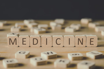 selective focus of medicine lettering on cubes surrounded by blocks with letters on wooden surface isolated on black
