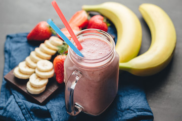 Smoothie with strawberry and banana in the jar at dark background