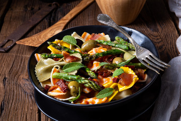 Pasta salad with green asparagus, olives and parma ham