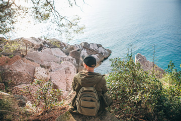 Obraz premium Tourist with a backpack near the sea. Travel alone. Looks into the distance.