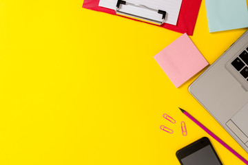 Laptop smartphone notepads clipboard sheet clips pencil colored background