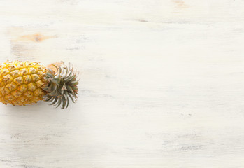 Ripe pineapple over white wooden background. Beach and tropical theme. Top view
