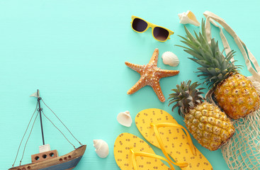 Ripe pineapple and beach sea life style objects over pastel mint blue wooden background. Tropical...