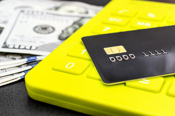 Сredit card on calculator keypad and dollar bills. Business concept.