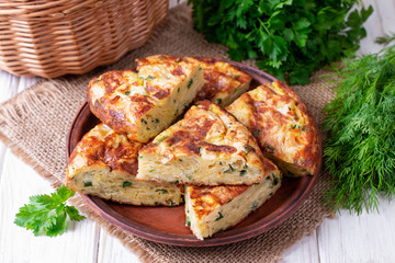 Pie with zucchini, cheese and herbs on the table