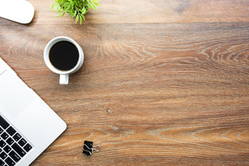 Wood office desk table with laptop computer, cup of coffee and supplies. Top view with copy space, flat lay.