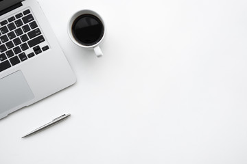 White office desk table with laptop computer, cup of coffee and pen. Top view with copy space, flat...