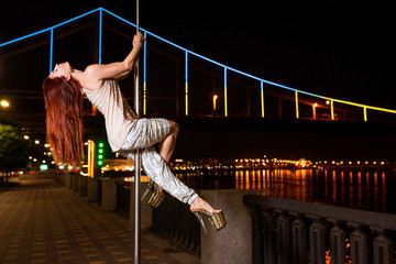 Fototapeta na wymiar Slim, fit, athletic beautiful redhead woman on Pedestrian bridge (Kyev, Ukraine) background at night