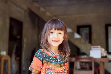 Authentic  portrait of pretty thai baby girl posing outdoors, dressed in traditional colorful dress, jewelry, being in good mood,smiling and looking at camera. Attractive child enjoying life