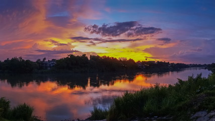 Naklejka na ściany i meble sunset at Mae Klong river, beautiful rever view evening of cloudy sky painted with vivid sun light in the sky background, Ban Pong City, Ratchaburi, Thailand.