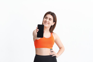 Young fitness woman posing isolated on a white background listening to music with wireless headphones.