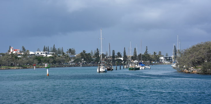 Moored yachts in the Mooloolaba marina on Mooloolah River on a sunny but cloudy day. Rock wall along Mooloolah river (Sunshine Coast, Queensland, Australia).