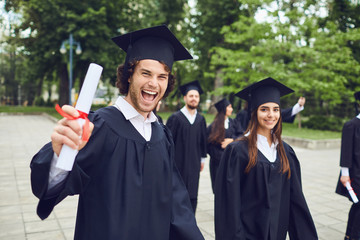Man graduate is smiling against the background of university graduates.
