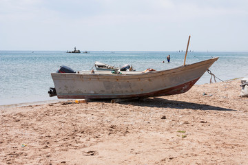 Obraz premium Old fishing boat with motor on the coast and in the sea water in summer.