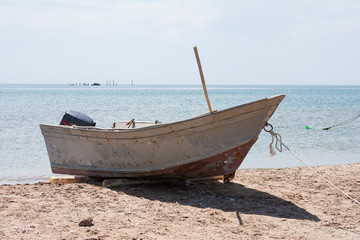 Old fishing boat with motor on the coast and in the sea water in summer.