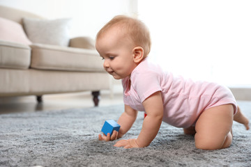 Cute baby girl playing on floor in room. Space for text