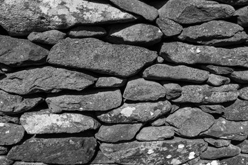 An image of a wall made up of large rocks ideal for background or textures, image is black and white, nobody in the image