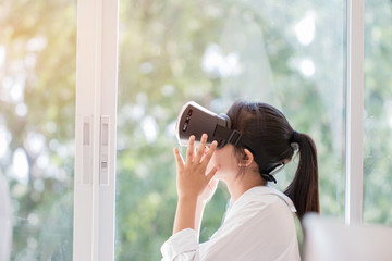 Virtual reality interaction headset by Asian Beautiful young female wearing touching air during VR box for playing game simulator future media. Technology digital Futuristic innovation device concept