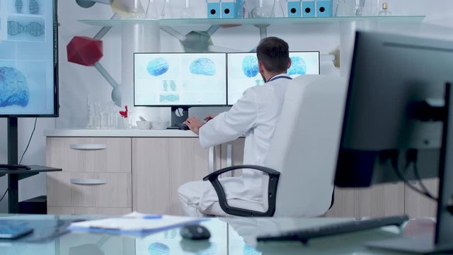 Doctor working in modern research center on a computer with 3D animated brain scans and DNA. Modern medicine and research in the future