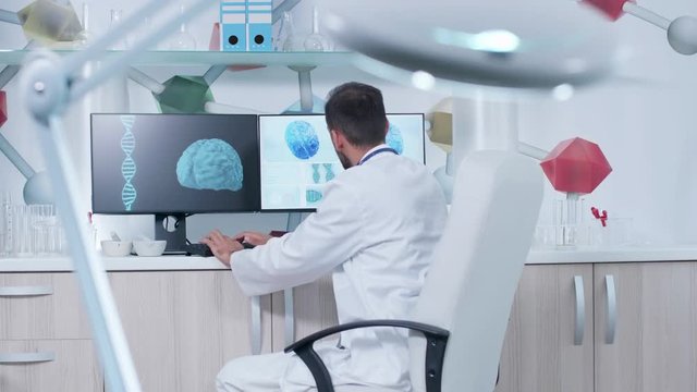 Doctor in modern office or research center working on a computer with animated 3D brain scans. Future of healthcare
