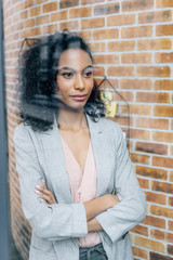Fototapeta premium african american Casual businesswoman with crossed arms looking through window in loft office