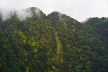 Waterfall in green forest and clouds above