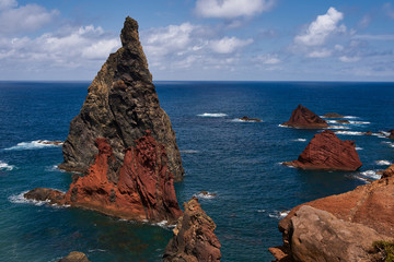 Brown red cliff in the blue atlantic ocean and waves