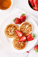 ThreeTasty Homemade Cottage Cheese Pancakes with Strawberries on White Plate Tasty Healthy Diey Breakfast Breakfast Concept Top View Flat Lay