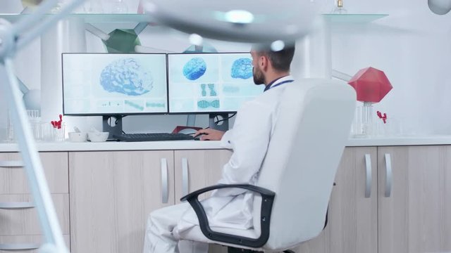 Doctor working in modern research facility with 3D brain scans showing on monitors. He study the human brain and DNA strings