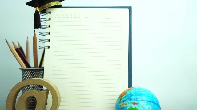 Empty notebook mockup for your image text with pencils, world globe, e-mail sign, graduation hat on white background. Concept of global business study abroad educational. Back to School.