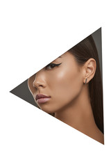 Cropped side geometric portrait of woman with black flicks. The young girl with dark hair is wearing silver stud earrings in the shape of thin rectangle, looking at camera behind triangle foreground.