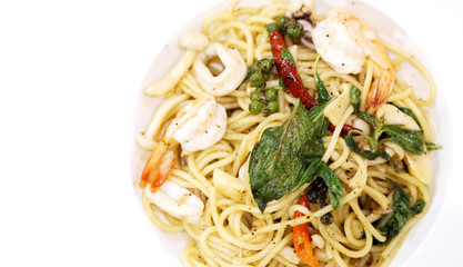 Top view seafood stir fried spicy spaghetti in white ceramic plate with copy space.