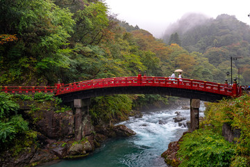 people walking aceoss a bridge over the river in nikko japan