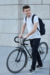 Handsome hipster man posing with bicycle in the city.