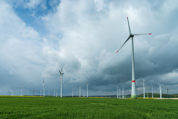 Windpark mit dramatischem Himmel und grünem Feld