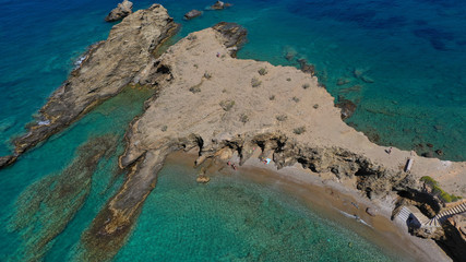 Aerial drone photo of iconic deep turquoise beach of Latinaki with crystal clear sea and rocky sea shore forming small caves, Folegandros island, Cyclades, Greece