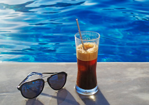 freddo espresso coffee with sunglasses in front of a pool - cold coffee - summer vacation