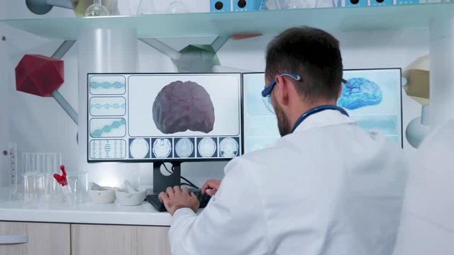 Man in research center working on computer with 3D brain scans