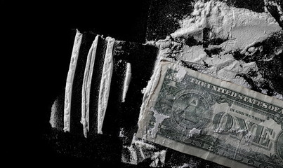One dollar and cocaine lines isolated on black background 